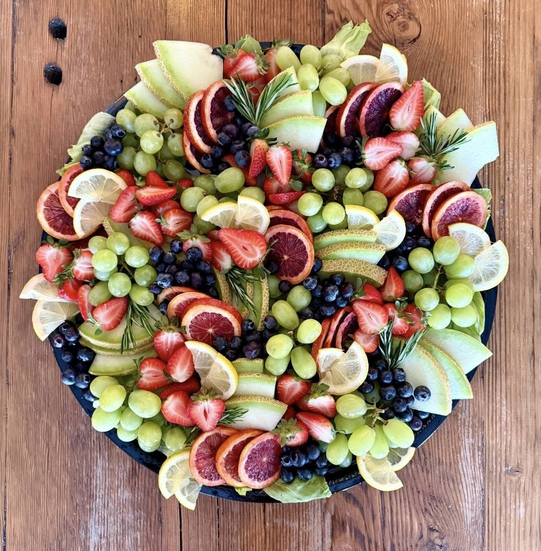 Round fruit platter with strawberries, blood oranges, grapes, melon and blueberries