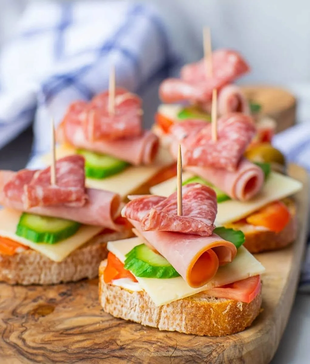 Appetizer bites of salami, ham, cheese and cucumber on toasted bread